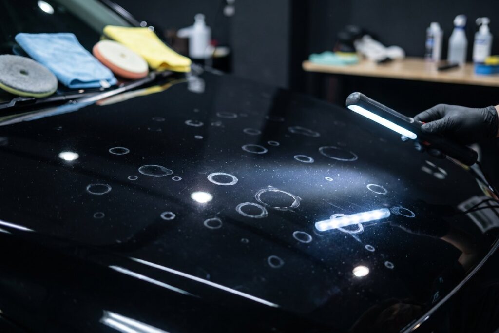 黒い車のボンネットに出たウォータースポット（白い輪じみ）にライトを当てたところ