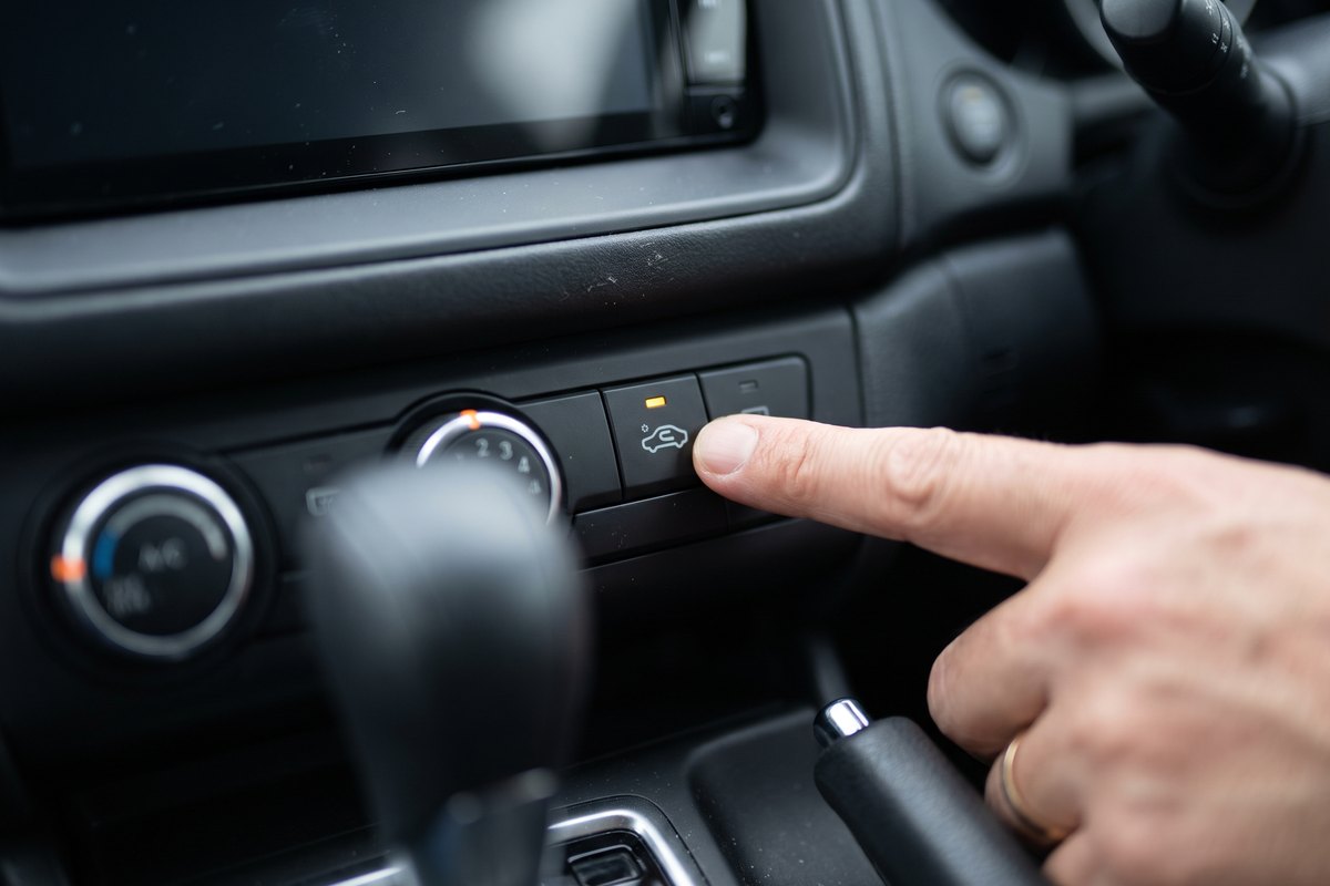 新車の臭い対策として、エアコンを外気導入に切り替えるボタンを押す指先