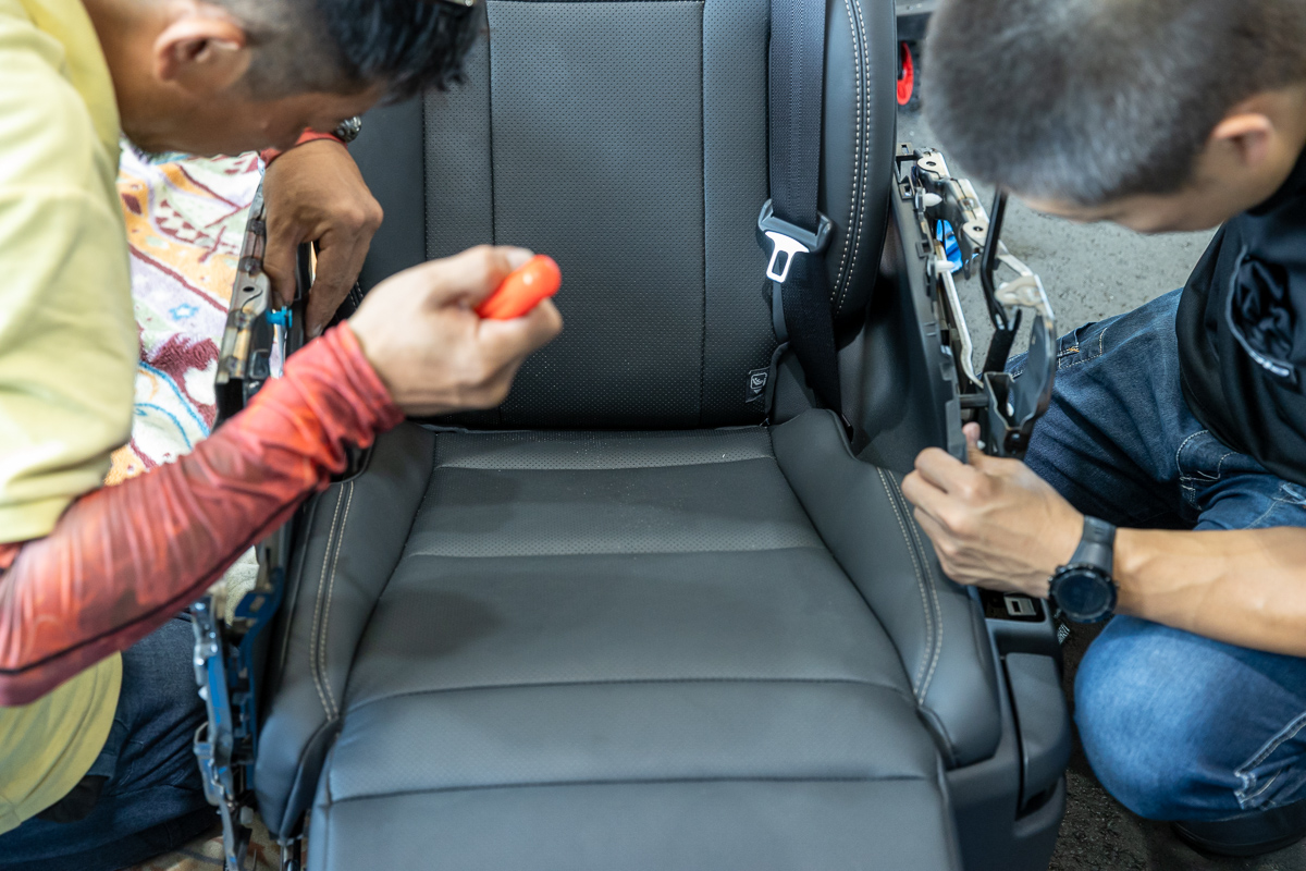 車から外したアルファードの2列目シートの横のカバーを、2人で外している