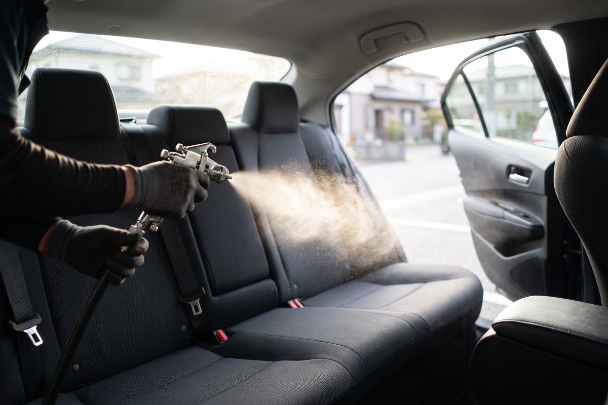 車内の後ろの席まわりに、専用のスプレーガンで噴霧しているところ